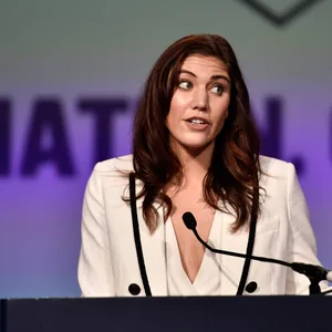 Ex-Torhüterin Hope Solo steht vor einem Pult und redet in ein Microfon