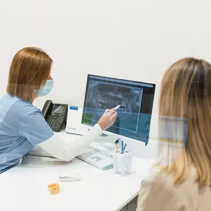 Ärztin in ihrer Praxis zeigt der Patientin eine Aufnahme auf dem Bildschirm.