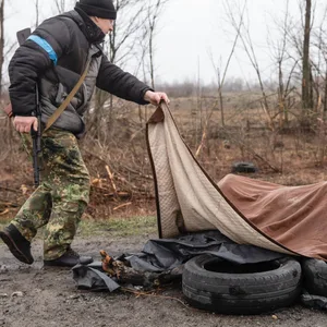 Ein ukrainischer Soldat breitet eine Decke über de Leichen mehrerer verbrannter Frauen in Butscha.