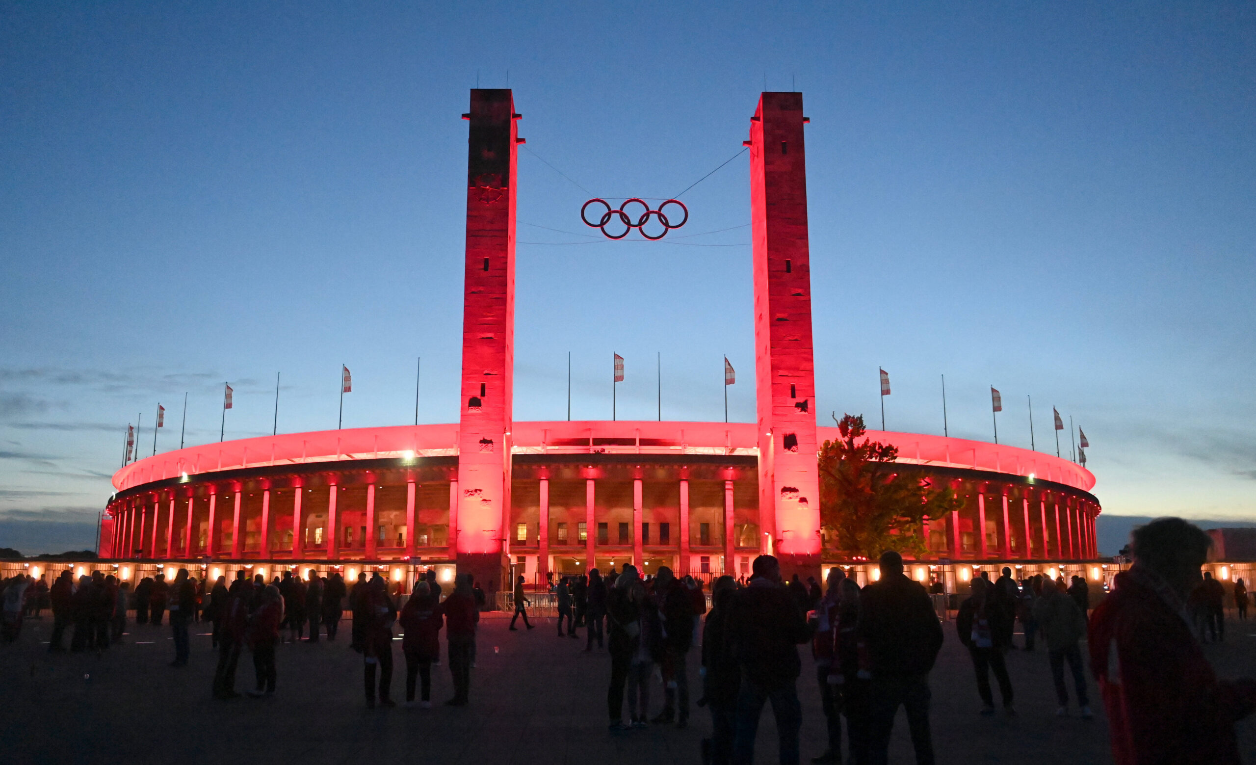 Das rot angestrahlte Olympiastadion in Berlin in der Abenddämmerung