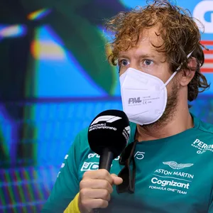 Sebastian Vettel beantwortet Fragen mit Mikrofon in der Hand und Maske über Mund und Nase