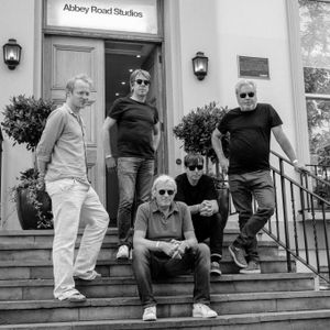 Die Band sitzt und steht auf der Treppe vor den Abbey-Road-Studios