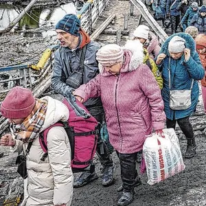 Menschen überqueren den Fluss Irpin auf einem improvisierten Weg unter einer durch einen russischen Luftangriff zerstörten Brücke, während sie aus der Stadt Irpin fliehen.