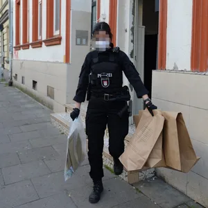 Eine Beamtin mit Tüten voller mutmaßlicher Beweise.