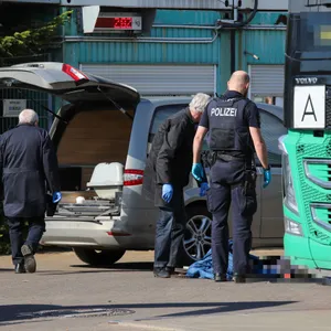 Einsatzkräfte stehen zwischen einem Lkw und einem Leichenwagen