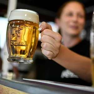 Eine Frau reicht ein gezapftes Bier über den Tresen