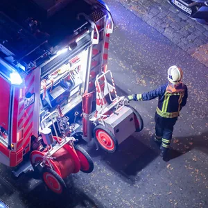 Ein Feuerwehrmann geht neben einem Feuerwehrauto her