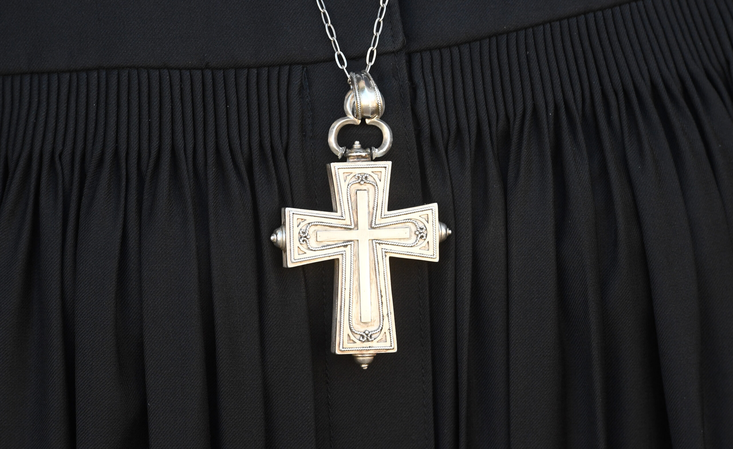 Ein Kreuz hängt über einem Talar.