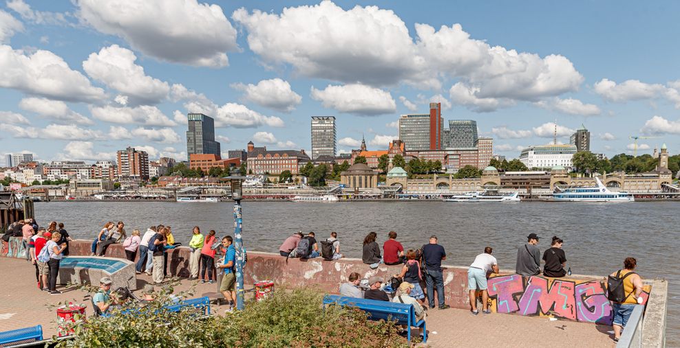 Ausflügler genießen bei leichtem Wind und Sonnenschein vom Aussichtspunkt Alter Elbtunnel aus den Blick über die Elbe.