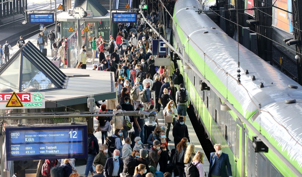 Ein grüner Zug steht im Hamburger Hauptbahnhof, viele Menschen stehen auf dem Bahnsteig