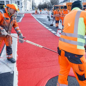 Arbeiter tragen rote Farbe auf einer neu eingerichteten Fahrradspur auf der Eslanade auf. (Archivbild)