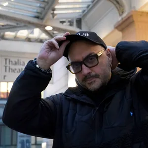 Kirill Serebrennikov steht draußen vor dem Thalia-Theater-Haupteingang, blickt in die Kamera und richtet sich seine Basecap