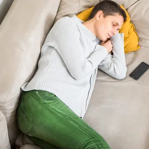 eine Frau liegt erschöpft auf dem Sofa.