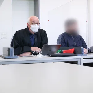 Die zwei Angeklagten sitzen zu Beginn des Prozesses vor dem Amtsgericht Harburg neben ihren Anwälten.