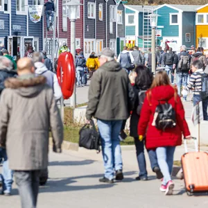 Helgoland-Besucher gehen nach ihrer Ankunft per Schiff über die Hafenstraße Richtung Inselzentrum.