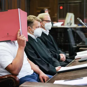 Der Angeklagte (links) sitzt im Strafjustizgebäude in Hamburg.