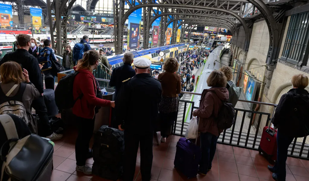 Zahlreiche Reisende stehen vor und auf einem Bahnsteig am Hamburger Hauptbahnhof.