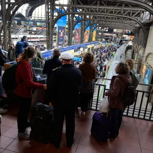 Zahlreiche Reisende stehen vor und auf einem Bahnsteig am Hamburger Hauptbahnhof.