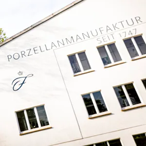 Ein Produktionsgebäude der Porzellanmanufaktur Fürstenberg steht hinter einem Wegweiser.