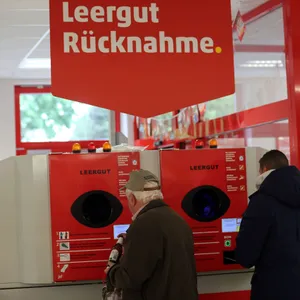 Männer geben Flaschen in einen Leergutautomaten