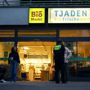 Ein Polizist befragt Zeugen vor dem Supermarkt in Hamburg-Eppendorf.