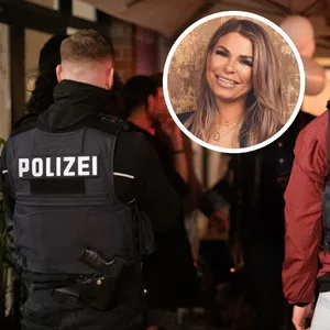 Zwei Polizisten stehen am Außenbereich eines Lokals, eingeklinkt eine lächelnde Frau