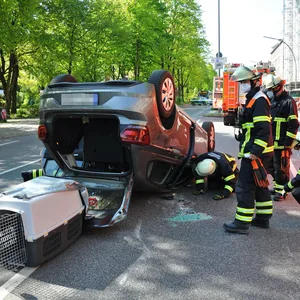 Feuerwehrkräfte überprüfen das auf dem Dach liegende Auto.