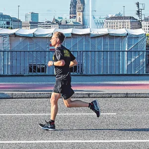 Zwei Jogger laufen an der Binnenalster vorbei.