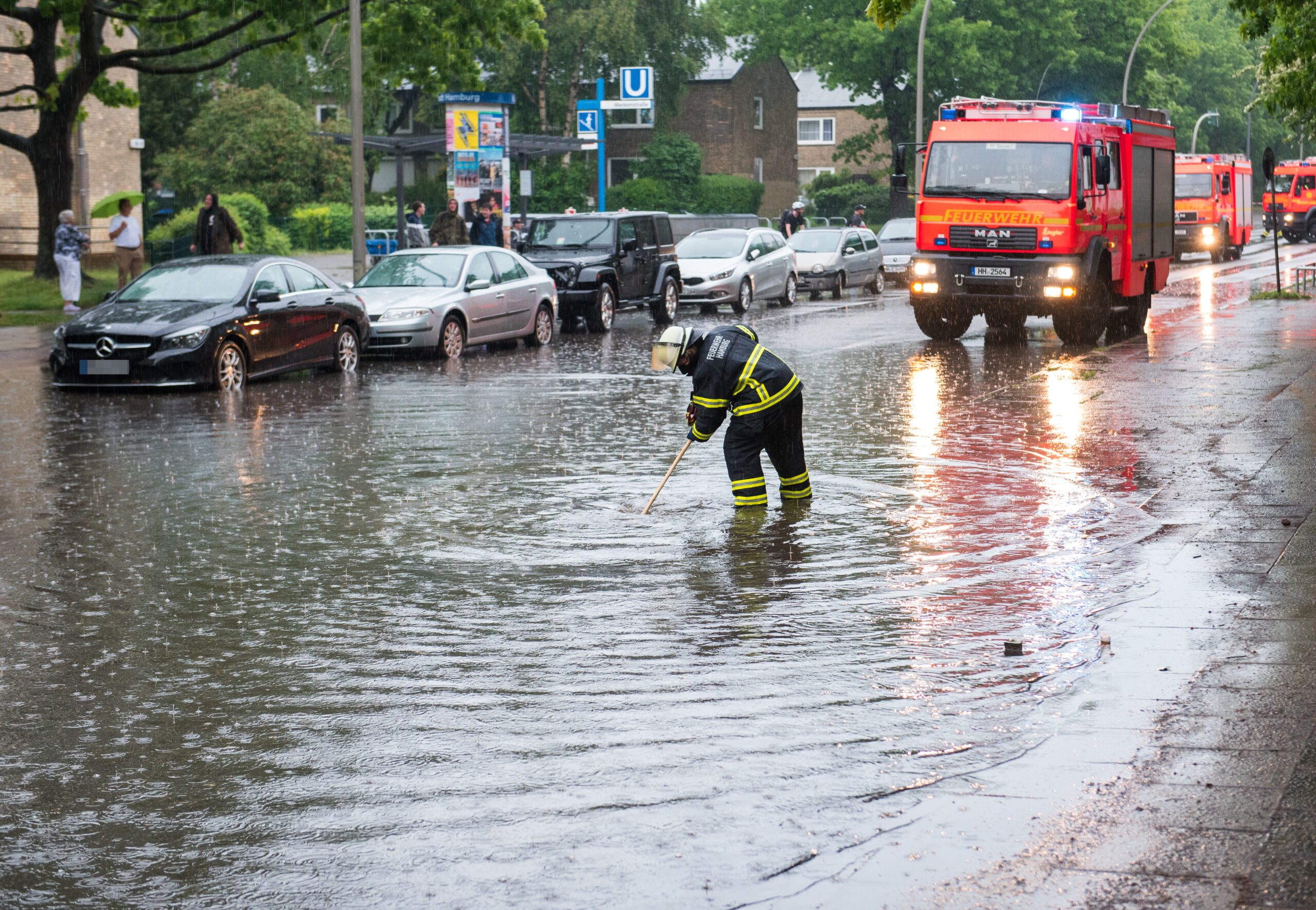 Eine Feuerwehrfrau steht in Billstedt auf einer von starkem Regen überfluteten Straße.