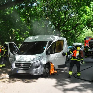Flammen schlagen aus der offenen Tür eines weißen Transporters.