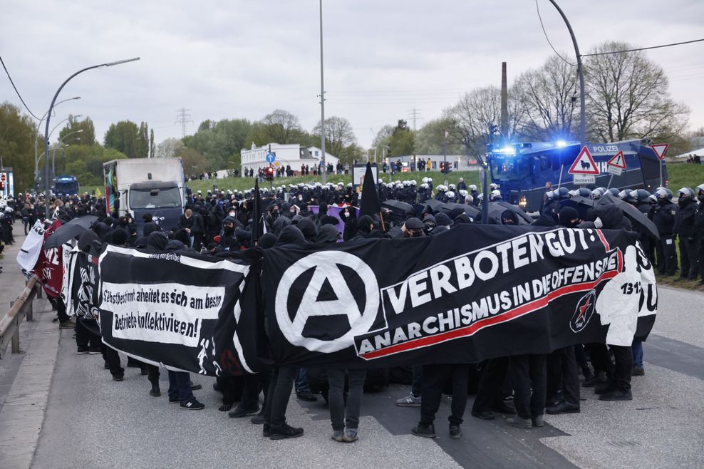 Demonstrierende halten Banner und haben Regenschirme aufgespannt