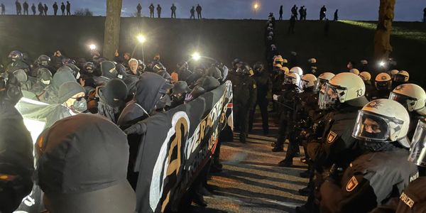 Demonstrierende des Aufzugs „Verboten gut – Anarchismus in die Offensive“ und Polizisten stehen sich auf der Harburger Chaussee gegenüber.