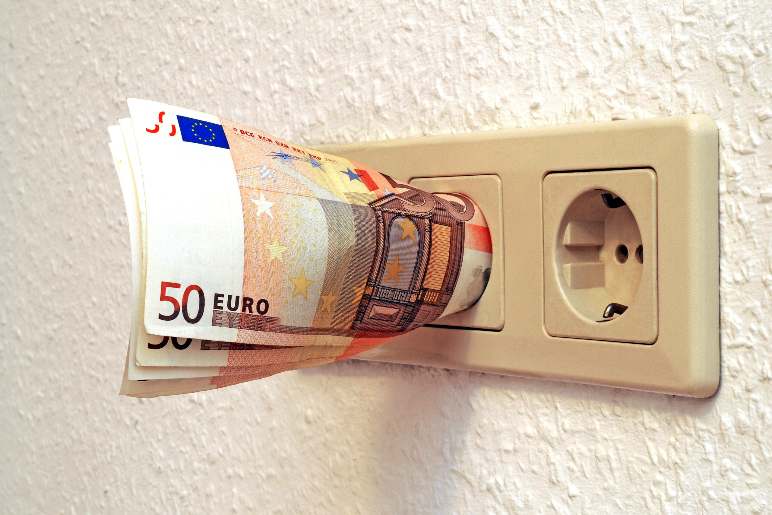 Die Energiepreise steigen und steigen. Für Anbieter gelten dennoch gewisse Regeln, mahnt die Verbraucherzentrale Hamburg. (Symbolbild): 50-Euro-Scheine stecken in einer Steckdose