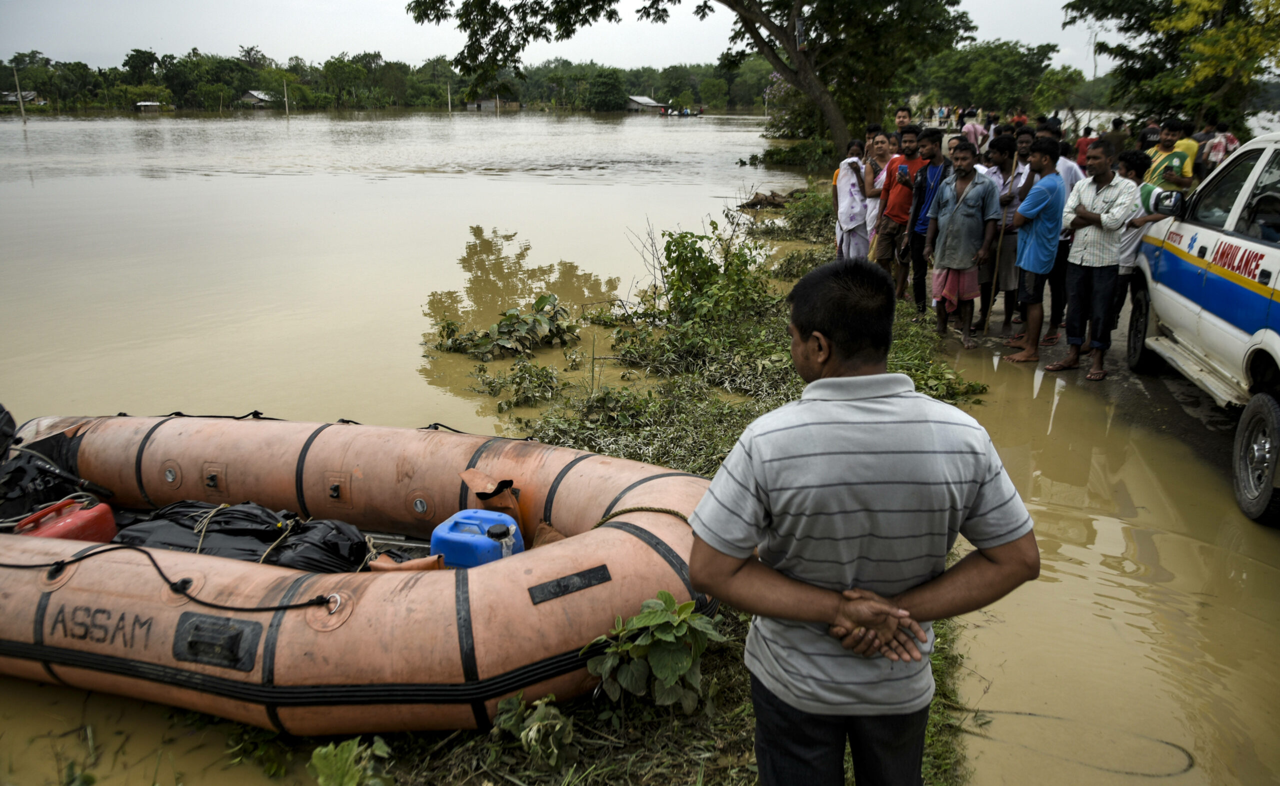 Im indischen Assam stehen die Bewohner neben der Leiche eines Jungen, der von der Flut getötet wurde.