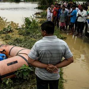 Im indischen Assam stehen die Bewohner neben der Leiche eines Jungen, der von der Flut getötet wurde.