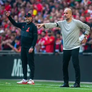 Pep Guardiola gestikuliert an der Seitenlinie, im Hintergrund Jürgen Klopp