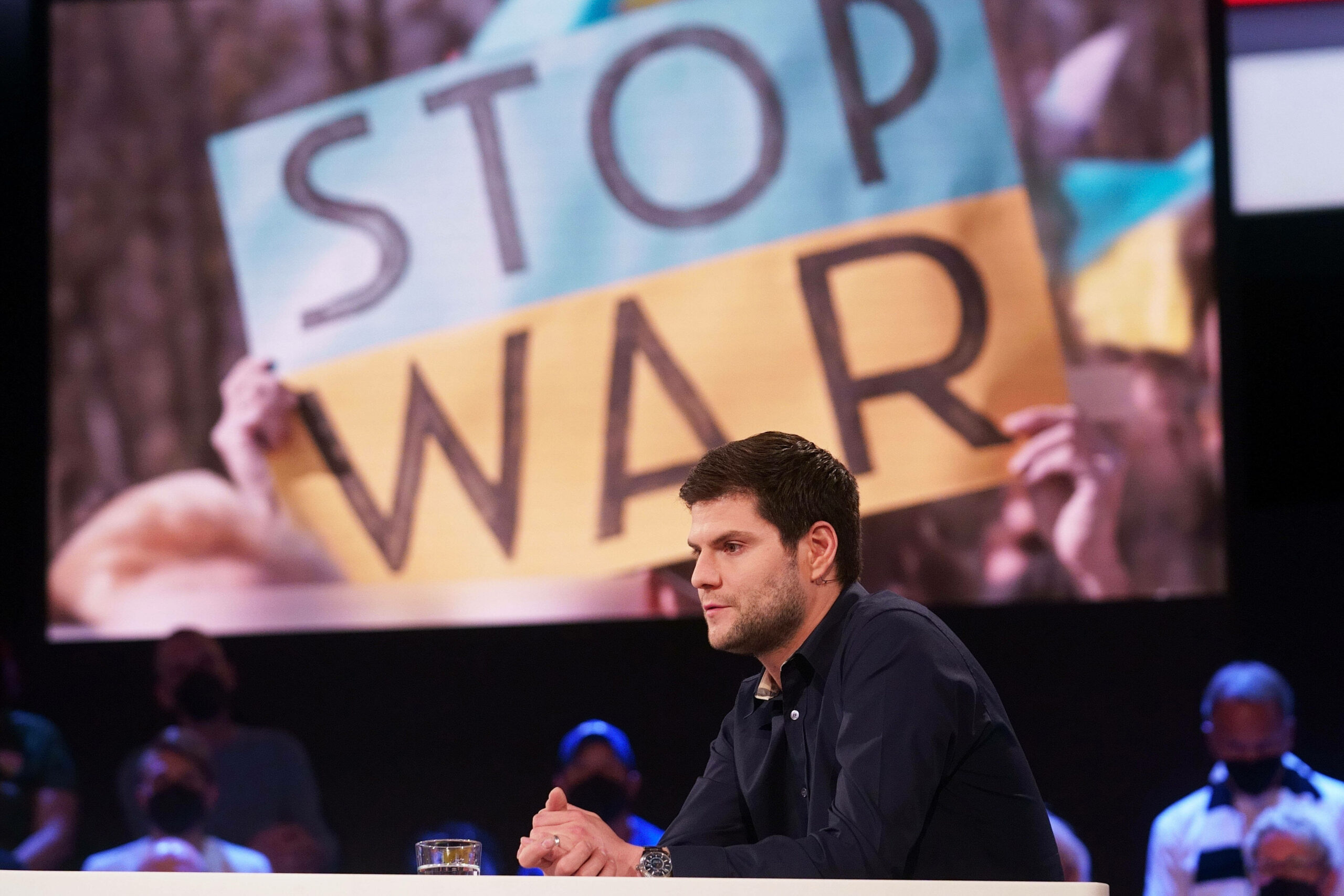Dimitri Ovtcharov im ZDF-Sportstudio, im Hintergrund wird ein „Stop War“-Plakat eingeblendet.