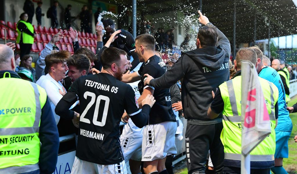 Spieler und Offizielle des FC Teutonia 05 feiern mit den Fans.