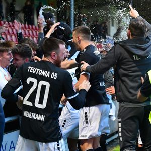 Spieler und Offizielle des FC Teutonia 05 feiern mit den Fans.