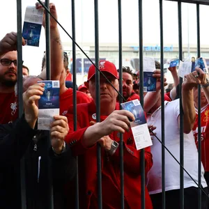 Fans des FC Liverpool zeigen ihre Eintrittskarten durch ein Gitter