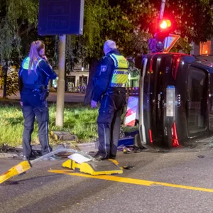 Polizisten begutachten das zur Seite gekippte Fahrzeug.
