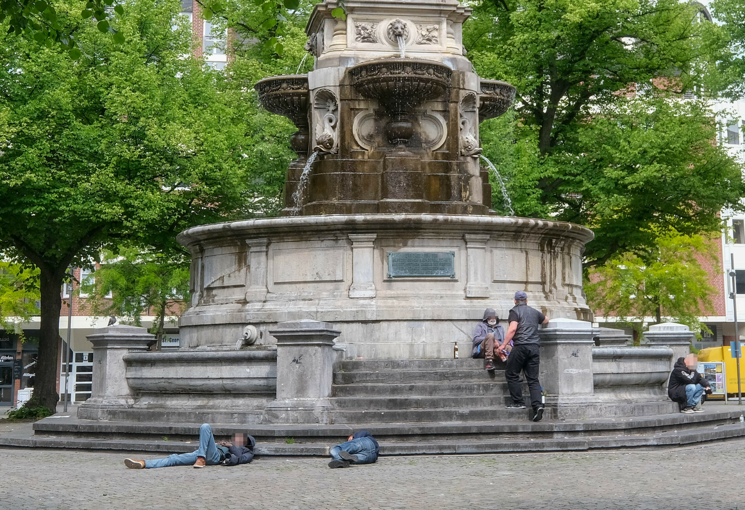 Alltag am Hansabrunnen: Einige schlafen ihre Rausch aus, andere trinken und sitzen.