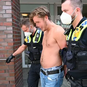 Polizisten führen den Mann in Handschellen ab.