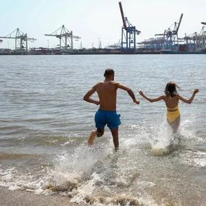 Zwei Menschen rennen in die Elbe.
