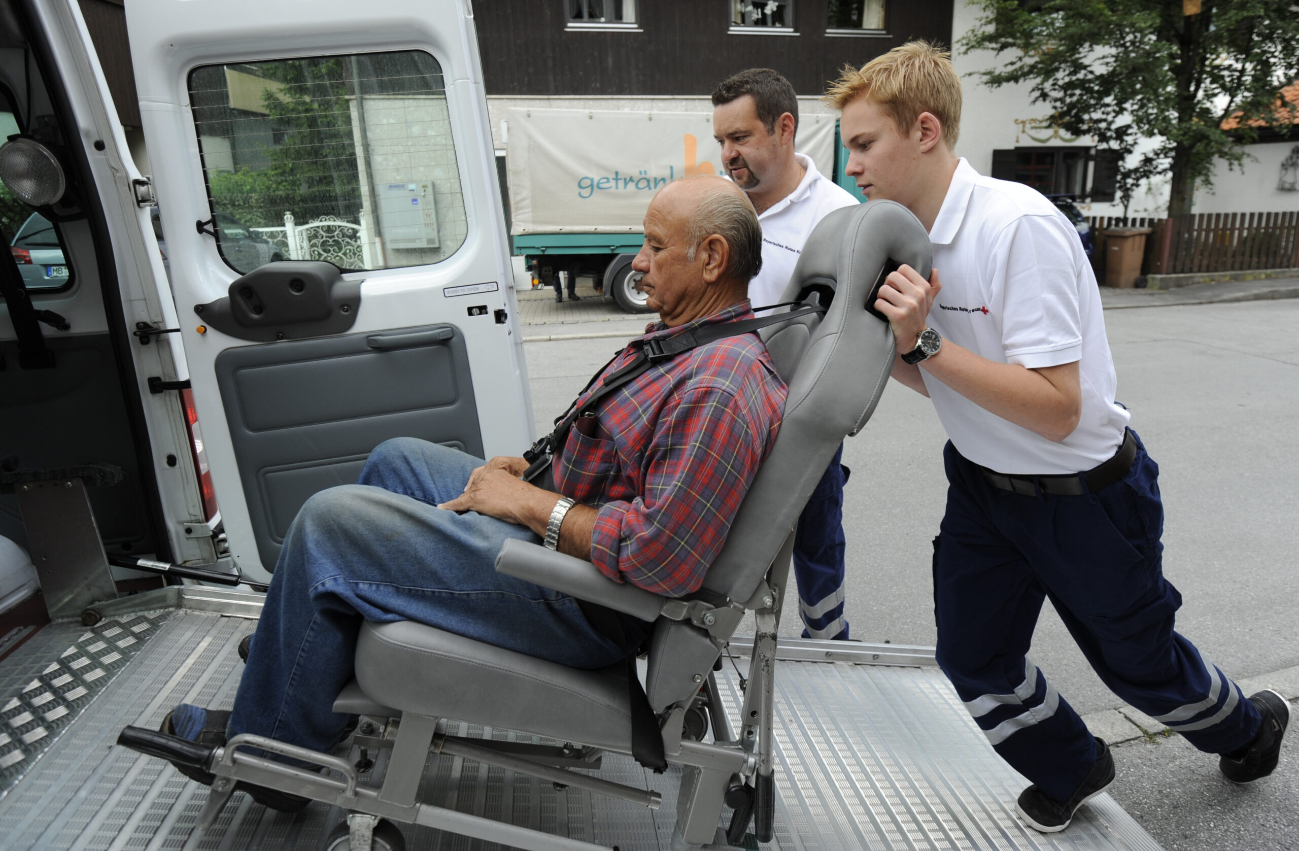 Ein Bundesfreiwilligendienstleistender schiebt einen älteren Herrn in einem Spezial-Rollstuhl.