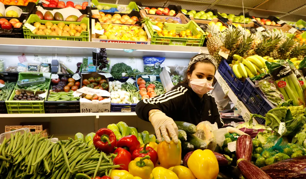 Eine Verkäuferin sortiert Obst und Gemüse auf einem Markt in Spanien.