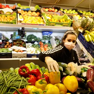 Eine Verkäuferin sortiert Obst und Gemüse auf einem Markt in Spanien.