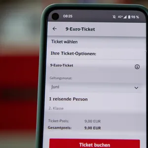 App mit 9 Euro Ticket vor einem fahrenden Zug.