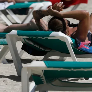 Menschen sonnen sich am Strand von Arenal.