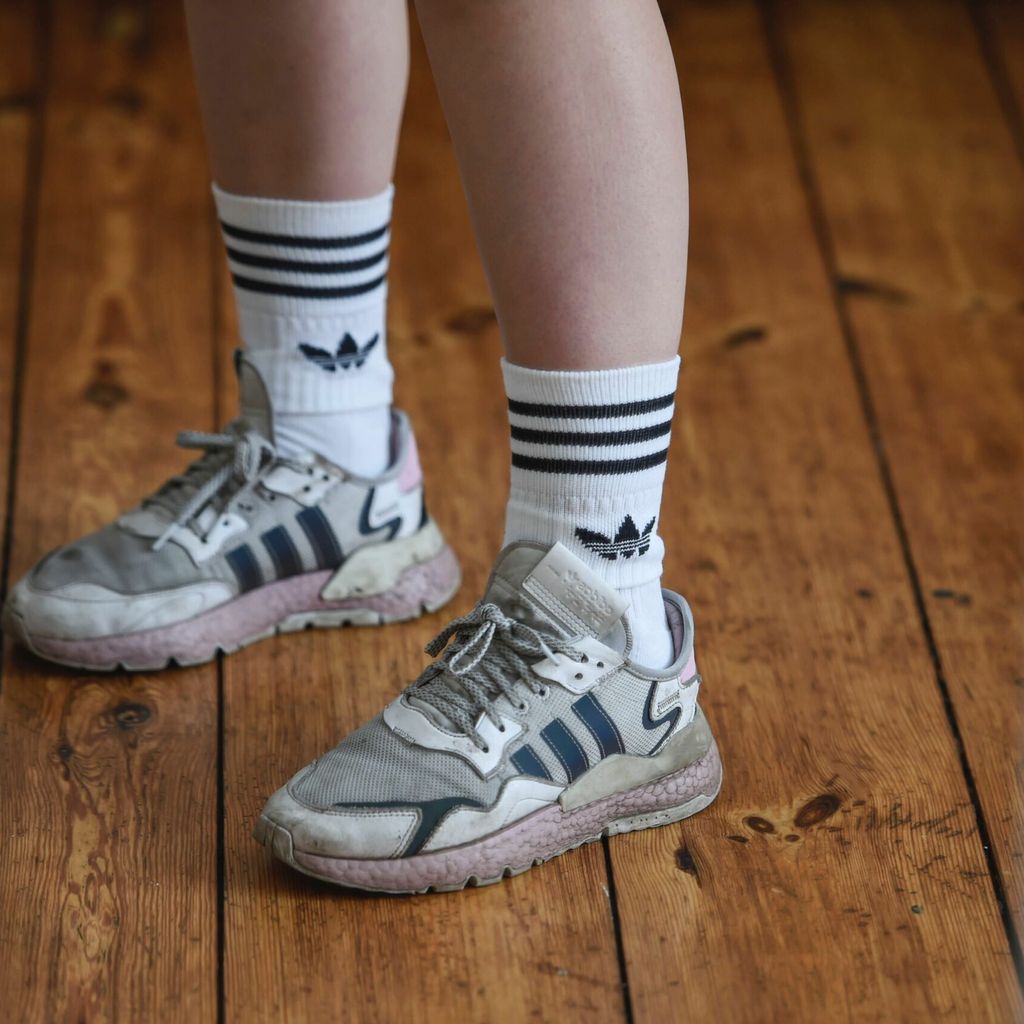Socken der Marke adidas werden in adidas-Turnschuhen getragen.